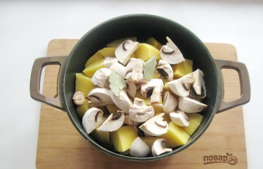 1. Этап. Курица с грибами в казане: Шампиньоны очистите, помойте, нарежьте не мелко и добавьте в казан. Посолите и поперчите по вкусу, добавьте лавровый лист. Добавьте воду.
