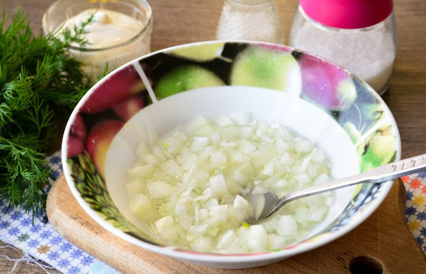 1. Этап. Теплый салат с баклажанами: Репчатый лук нарежьте кубиками, залейте водой, смешанной с уксусом, солью и сахаром. Оставьте лук мариновать на 15 минут, затем жидкость слейте.