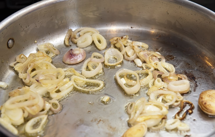 1. Этап. Стручковая фасоль с перцем: Разогреваем в сотейнике оливковое масло и обжариваем на среднем огне нарезанный кольцами лук до золотистого цвета.