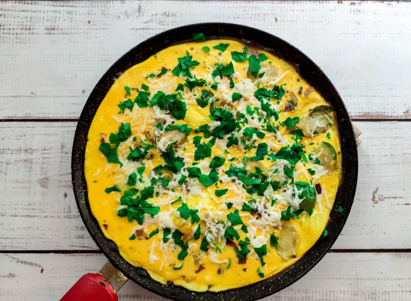 1. Этап. Омлет с брюссельской капустой: В конце посыпьте омлет тертым сыром, мелко нарезанной зеленью и жарьте до готовности.