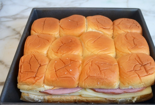 1. Этап. Булочки с сыром и ветчиной: На нижнюю часть булочек нанесите горчицу. Затем выложите кусочки сыра и ветчину. Сверху закройте ингредиенты верхней булочкой. Переложите булочки в форму для выпечки.