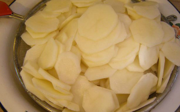 1. Этап. Картофельная запеканка со сметаной: 1. Картофель тщательно промойте под проточной водой, очистите от кожуры и аккуратно нарежьте ломтиками средней толщины. Посолите картошку, разотрите её руками так, чтобы соль равномерно распределилась.