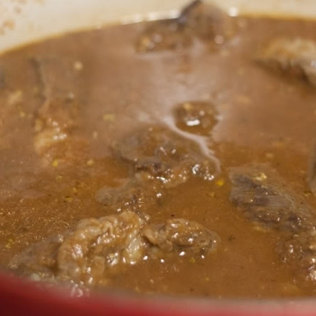 1. Этап. Гуляш из говядины: 8. В утятницу выложите содержимое сковороды, добавьте куриный и говяжий бульон, лавровый лист, тмин и майоран, все перемешайте. Туда же сложите мясо, накройте крышкой и отправляйте в духовку.