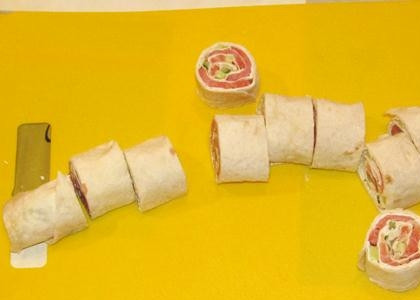 1. Этап. Рулет из лаваша с семгой и сыром: Острым ножиком режем трубочку лаваша с начинкой на маленькие рулетики.