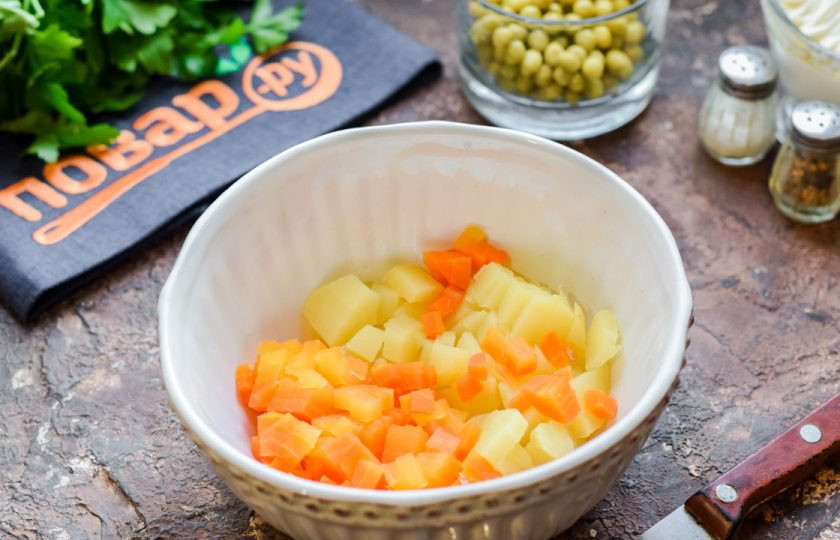 1. Этап. Оливье с курицей и авокадо: Очистите картофель и морковь, нарежьте небольшими кубиками и переложите в салатник.