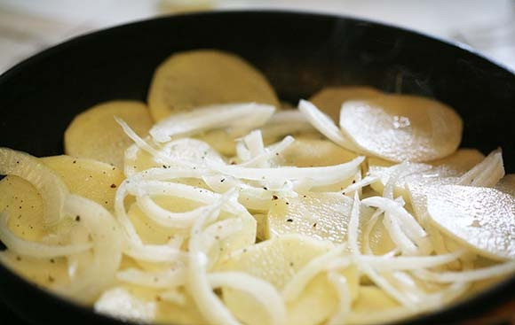 1. Этап. Домашняя жареная картошка с луком: 2. Посолите немного и поперчите, выложите снова картофель, слой лука. Накройте сковороду крышкой и обжаривайте на среднем огне 5-10 минут.