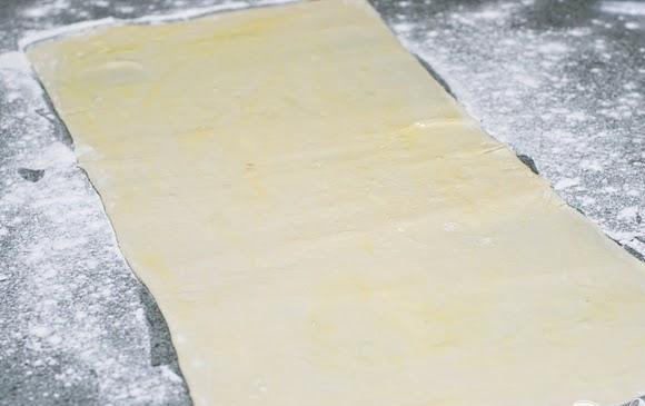 1. Этап. Палочки с корицей: 1. В средней миске смешать сахар с корицей, оставить в сторону. Дать листам слоеного теста разморозиться при комнатной температуре. Разогреть духовку до 200 градусов и выстелить 2 противня пергаментной бумагой или силиконовыми ковриками. Оттаявшие листы слоеного теста раскатать в прямоугольники размером около 30Х50 см, смазать их взбитым яйцом.