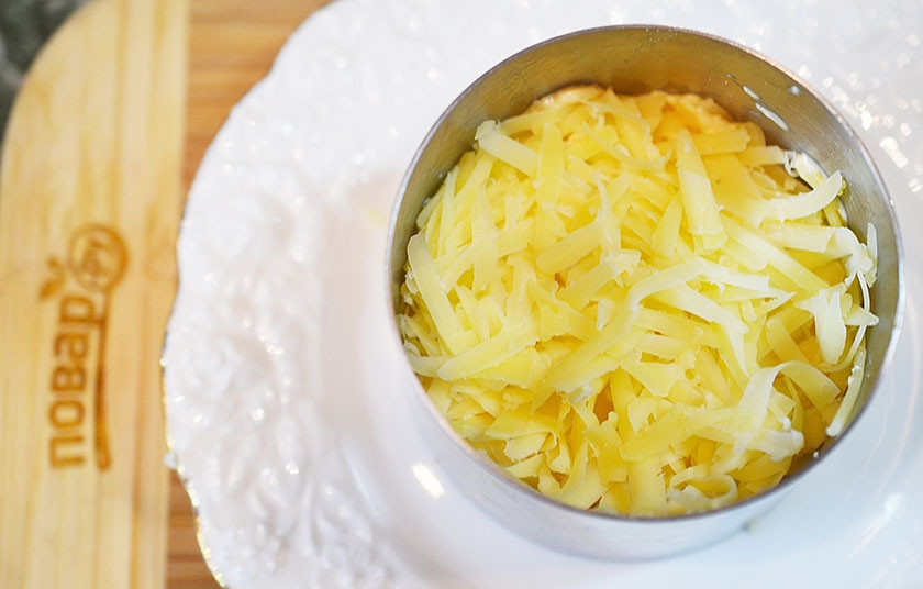 1. Этап. Новогодний салат Королевский: Следующим слоем — натертый сыр и немного заправки.