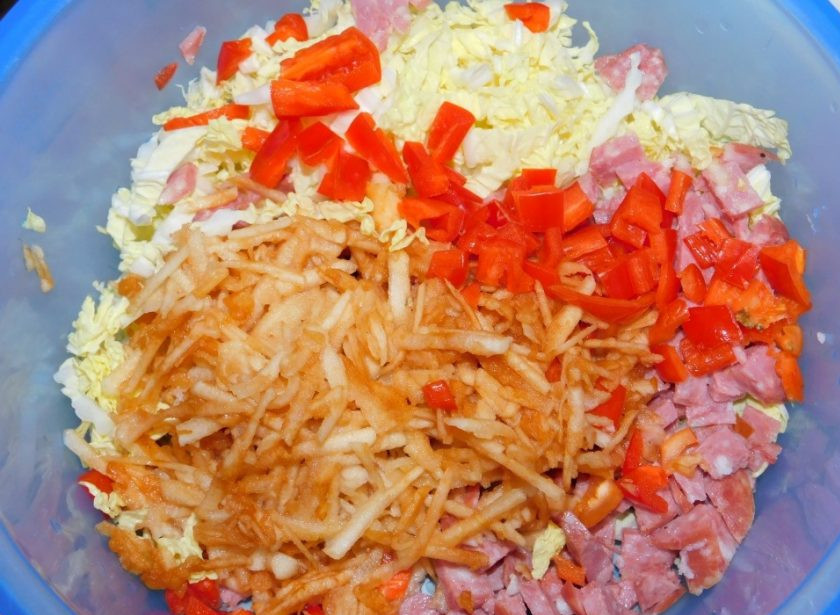 1. Этап. Овощной салат с колбасой: Добавьте нарезанный болгарский перец, тертое яблоко и маринованный лук. Заправьте салат майонезом и перемешайте.