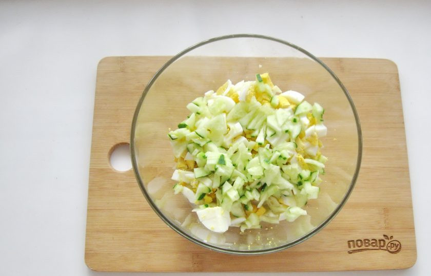 1. Этап. Салат из цветной капусты с крабовыми палочками: Свежий огурец нарежьте небольшими кубиками, добавьте в салат.