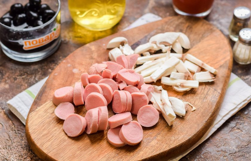 1. Этап. Солянка Барская: Сосиски очистите от пленки, нарежьте кружочками. Грибы нарежьте пластинами.