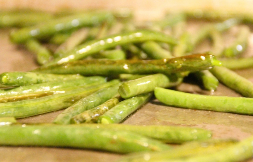 1. Этап. Запеченная стручковая фасоль: Обрежьте хвостики стручковой фасоли с обеих сторон. Полейте их оливковым маслом, посолите, поперчите, выложите в форму для выпекания. Выпекайте 10 минут в разогретой на 200 градусов духовке. Через 10 минут достаньте стручковую фасоль и перемешайте. Положите обратно в духовку и запекайте ещё 10-12 минут, пока стручковая фасоль не покроется золотистой корочкой.