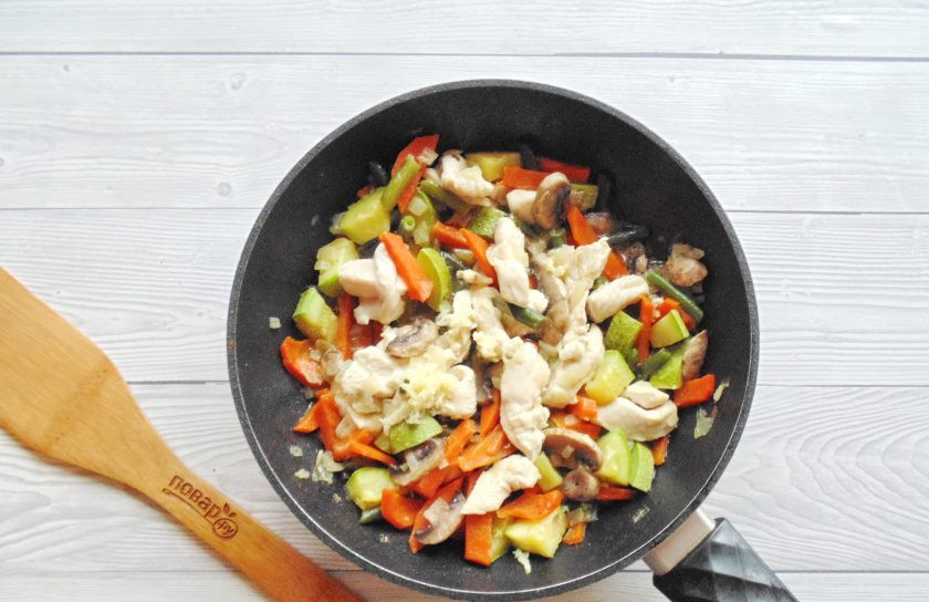 1. Этап. Куриное филе с овощами на сковороде: Накройте сковороду крышкой и тушите филе с овощами 7-8 минут до готовности. В конце приготовления добавьте измельченный чеснок.