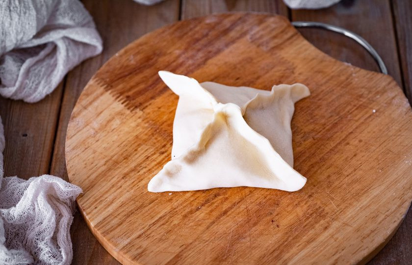 1. Этап. Хачапури из слоеного теста с сыром и творогом: Сложите тесто конвертиком и закрепите пальцами края.