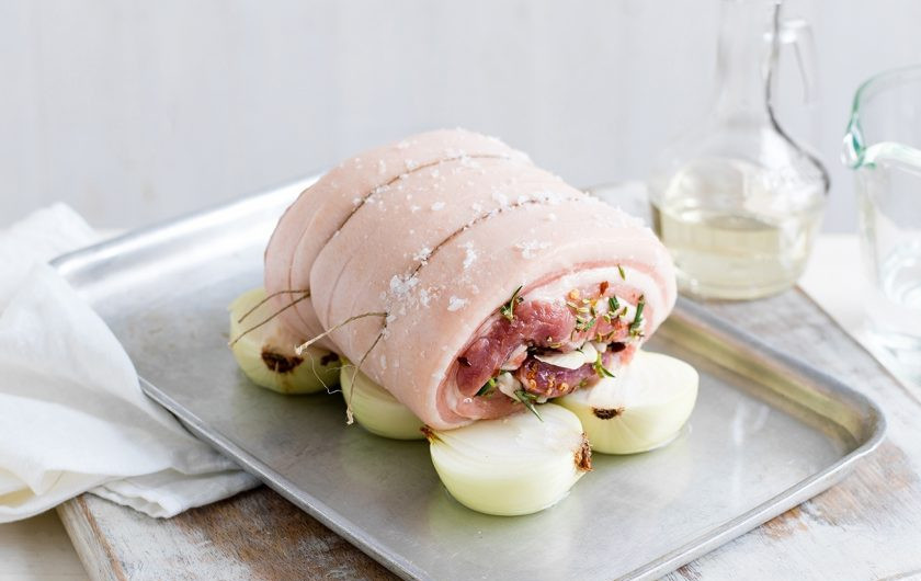 1. Этап. Итальянская поркетта: 4. Сверните свинину в рулет и положите на подушку из лука.