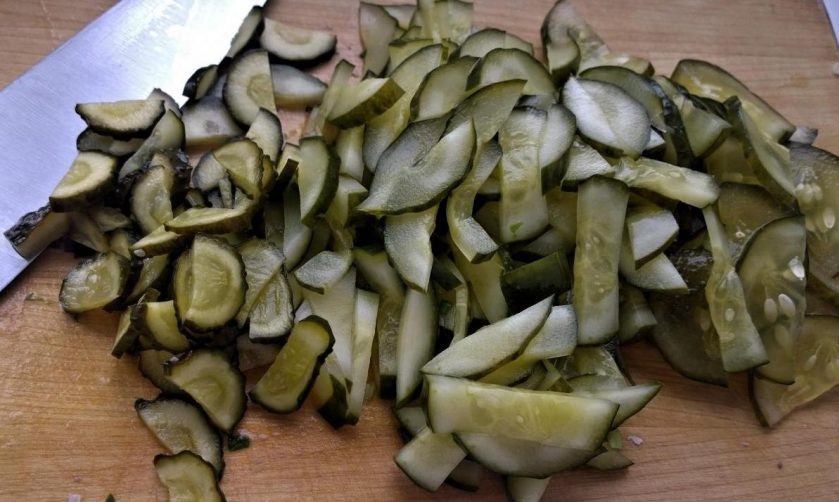 1. Этап. Салат с кальмарами и солеными огурцами: Огурцы тонко нарежьте, а зелень измельчите.