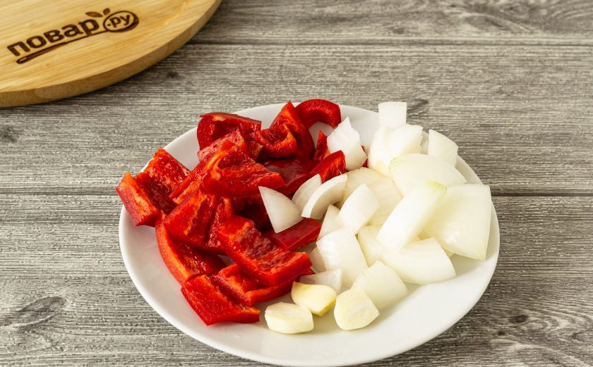 1. Этап. Соус для пиццы на зиму: Болгарский перец помойте, удалите семена и хвостик. Нарежьте небольшим ломтиками. Чеснок очистите. Лук нарежьте кубиками среднего размера.