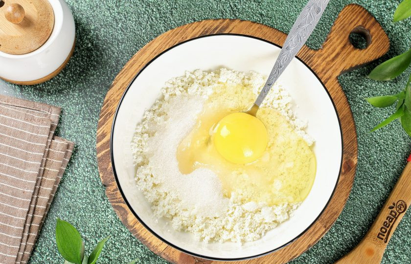 1. Этап. Пирожные Лотосы с творогом и сухофруктами: Творог перетрите через сито или хорошо разомните вилкой. Добавьте яйцо и сахар.