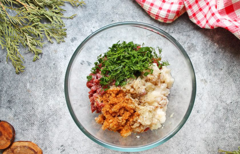 1. Этап. Манты из лосятины: Репчатый лук порежьте и пропустите тоже через мясорубку, добавьте к мясу. Все посолите, поперчите, добавьте специи и резаную зелень. Все хорошо перемешайте до равномерного распределения. Если фарш очень жесткий, добавьте немного холодной воды или мелко колотый лед. Это позволит сделать фарш сочным.