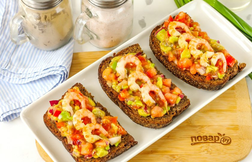 1. Этап. Брускетта с гуакамоле и креветками: Креветки очистите от панциря, выложите на гуакамоле в любом порядке. По желанию — можете их тоже мелко нарезать.