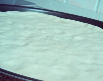 1. Этап. Фокачча тонкая: Когда тесто поднимется, обомните его руками. Форму для запекания (чем больше диаметр, тем лучше) смажьте маслицем. Затем выложите на нее тесто и растягивайте руками, пока оно не дойдет до бортов. Оставьте тесто подниматься на двадцать минуток.