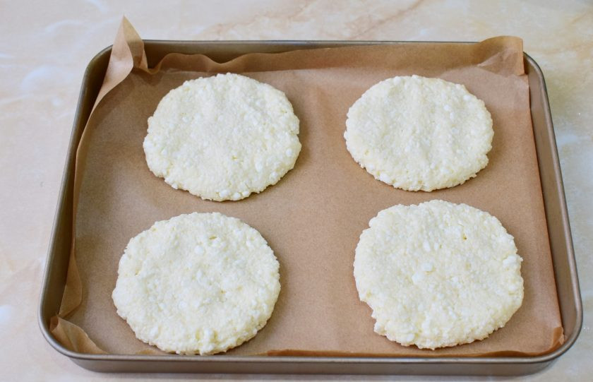 1. Этап. Творожные лепешки в духовке: Противень для выпечки застелите пергаментом. Руки намочите или смажьте растительным маслом. Сформируйте лепешки и выложите их на противень. Выпекайте лепешки при температуре 180 градусов 15-20 минут. Ориентируйтесь по своей духовке.