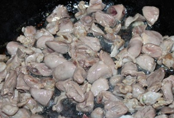 1. Этап. Жаркое из куриных потрохов: В большой сковороде раскалите растительное масло и обжарьте куриные желудочки, постоянно помешивая. Через 5 минут добавьте кусочки сердечек. Еще через 5 минут добавьте печень и обжаривайте еще 3 минуты. Посолите и поперчите.