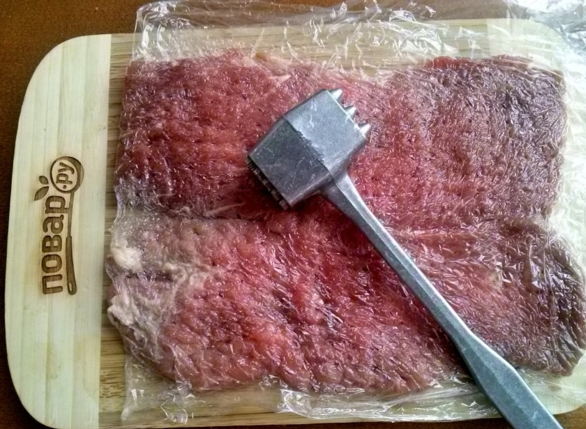 1. Этап. Новогодний рулет из говядины: Мясо посолите и поперчите по вкусу. Накройте пищевой пленкой и отбейте молоточком. Для удобной порционной подачи я разделила мясо на два кусочка.
