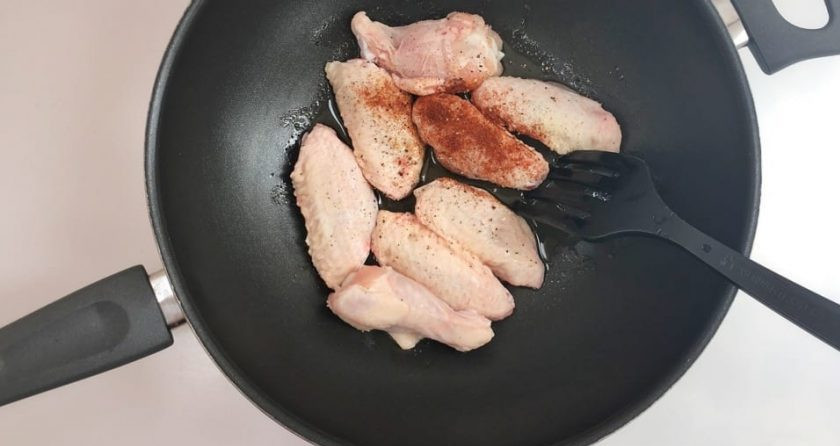 1. Этап. Крылышки на сковороде: 2. Вымойте крылья и разогрейте отдельно сковороду со столовой ложкой растительного масла. Выложите крылышки, добавьте соль, красный и черный перцы.