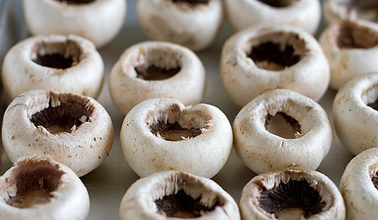 1. Этап. Шампиньоны под шубой: 3. Грибы вымойте, обсушите, удалите ножки. В этом блюде они вам не понадобятся. Смажьте чуточкой масла жаропрочную форму и выложите шампиньоны отверстием вверх.