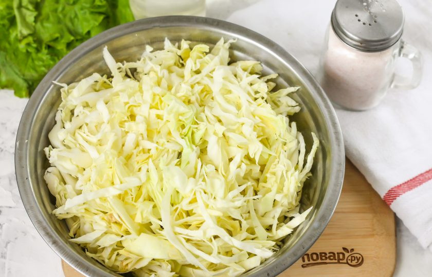 1. Этап. Молодая квашеная капуста: Промойте половину вилка квашеной капусты в воде, стряхните лишнюю влагу. Если у вас большая семья, то вы можете заквасить и целый вилок, но помните, что его нужно съесть в течение 2-3 дней после заквашивания, так как такая закуска надолго не заготавливается. Нарежьте овощ лентами и выложите нарезку в глубокую емкость.