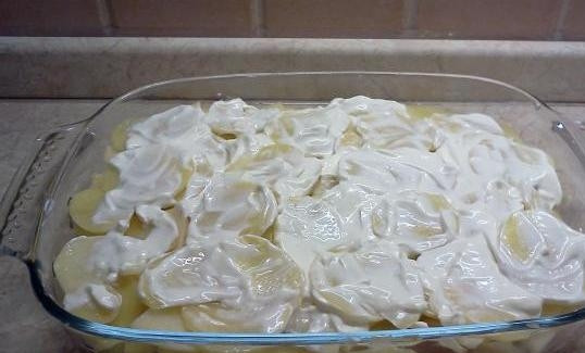 1. Этап. Запеченный минтай: Далее укладываем нарезанный слайсами картофель, хорошенько солим его и обмазываем смесью из сметаны и майонеза (для остроты вкуса - в смесь можно добавить мелко нарубленного чеснока).