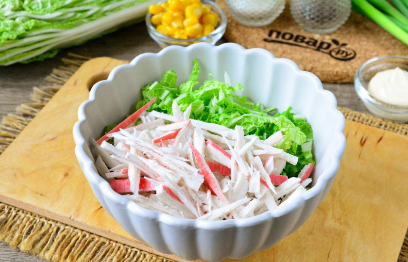 1. Этап. Салат с сыром, крабовыми палочками и пекинской капустой: В подходящую посуду выложите нарезанную капусту и крабовые палочки.