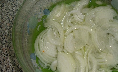 1. Этап. Салат Женская слабость: Очищаем луковицу и нарезаем тонкими полукольцами. Заливаем кипятком минут на 10, затем воду сливаем.