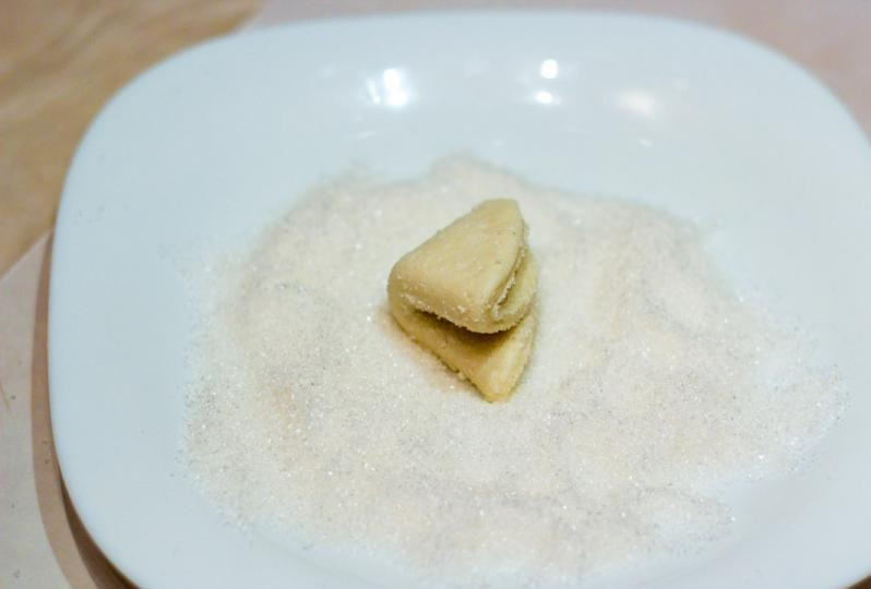 1. Этап. Творожное печенье Ушки: Затем изделие ещё раз сверните вдвое сахарной частью внутрь. А с внешней стороны обмакните его в сахаре. Тесто придавите.