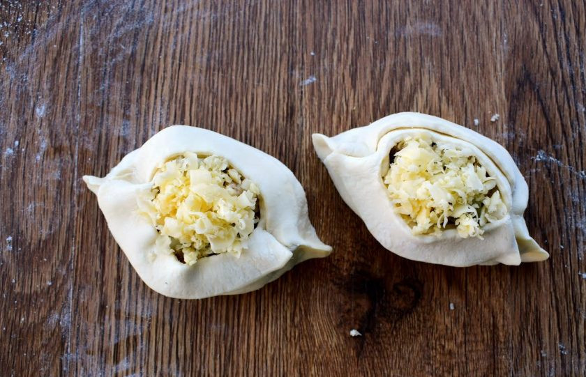 1. Этап. Лодочки из слоеного теста: 5. В центр заготовки поместите начинку, сверху посыпьте тертым сыром. Сформируйте лодочки. Потяните полоски к центру, перекрестите над начинкой и расположите их внахлест на противоположные края.