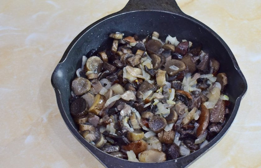 1. Этап. Печень в горшочках по-русски: Добавьте в сковороду грибы и обжарьте их вместе с луком 5-7 минут. Из грибов выпарится лишняя влага. Посыпьте грибы солью и специями.