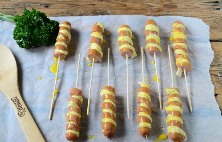 1. Этап. Сосиски в тесте на палочке Твистер: Выложите сосиски в тесте на пергамент, смажьте взбитым яйцом. Также можно присыпать кунжутными семечками. Запекайте сосиски в тесте в духовке при температуре 180 градусов 20-25 минут.