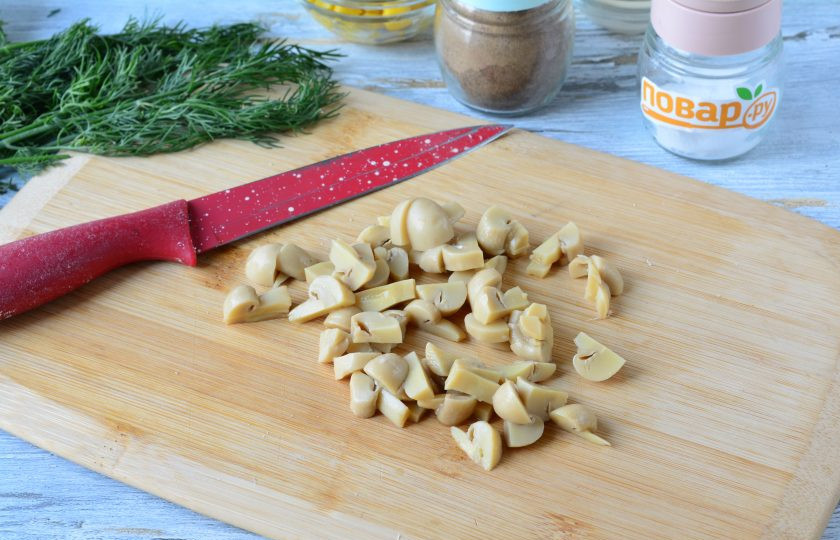 1. Этап. Салат с маринованными грибами и кукурузой: Нарежьте средними кусочками маринованные шампиньоны.