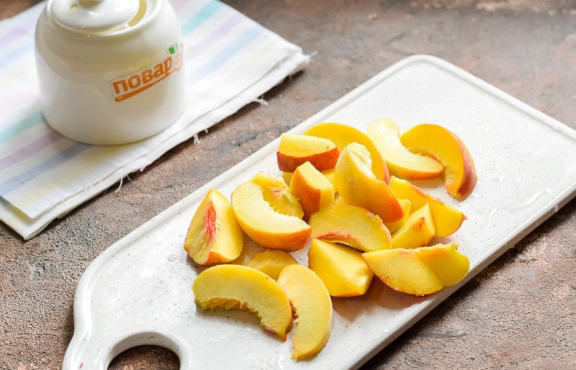 1. Этап. Компот из вишни и персиков на зиму: Персики вымойте и разрежьте пополам, удалите косточки. Нарежьте персики дольками.