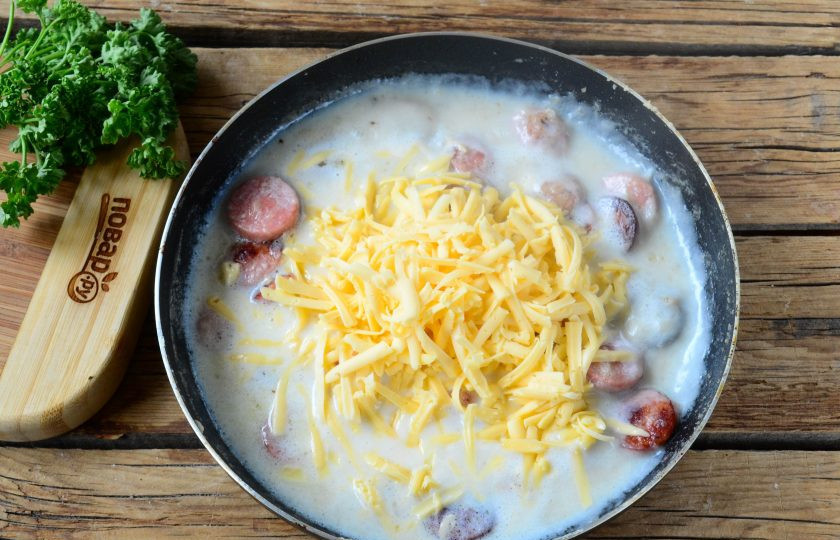 1. Этап. Хот-дог в луковых колечках: Отправьте в сковороду натертый на крупной терке сыр, перемешайте полученную массу до максимальной однородности.