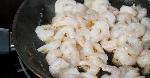 1. Этап. Салат с креветками американский: В той же сковороде быстро обжарьте креветки и добавьте чеснок. Креветки должны порозоветь. Снимите с огня.