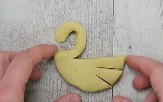 1. Этап. Песочное печенье Лебеди: 6. Отогните верхнюю полоску теста и сформируйте шею и головку лебедя. «Крылья» слегка отогните.
