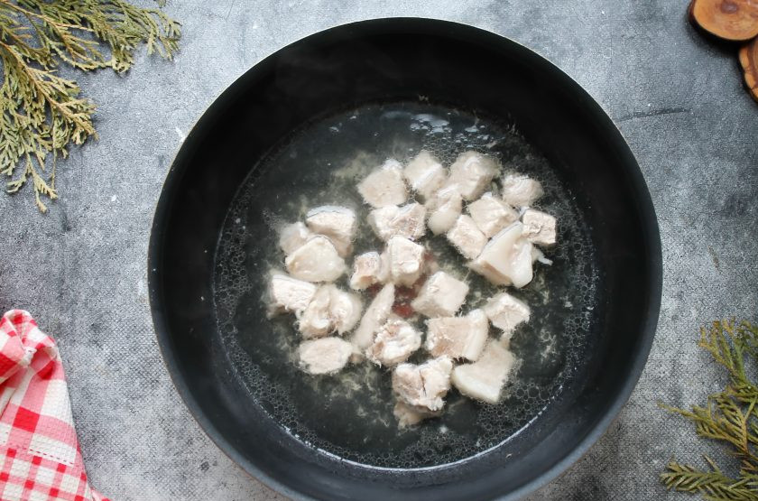 1. Этап. Кулеш Солдатский: Свинину вымойте, удалите кости и порежьте на кусочки, выложите в кастрюлю. Влейте к мясу воду, посолите и отварите в течение 20 минут на среднем огне, снимая пену. Пока варится мясо, обжарьте мелко нарезанный репчатый лук на растительном масле в течение 5-7 минут.