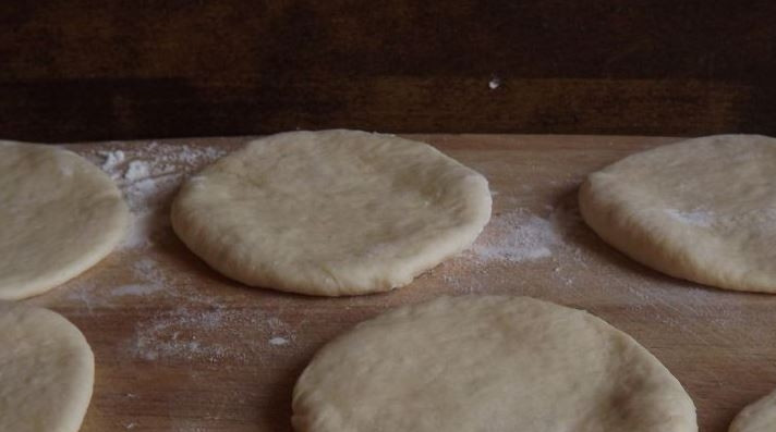 1. Этап. Пирожки с яйцом и зеленым луком: Шарики теста выложите на рабочую поверхность, предварительно присыпав ее мукой. Затем раскатайте их в кружочки одинакового размера.