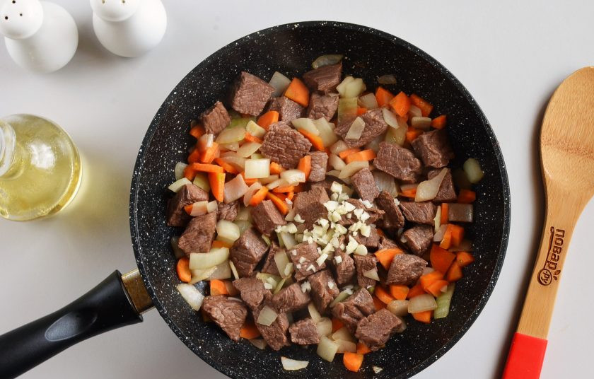 1. Этап. Тушеная телятина с подливкой: Добавьте мелко рубленый чеснок. Перемешайте, одну минутку обжарьте.