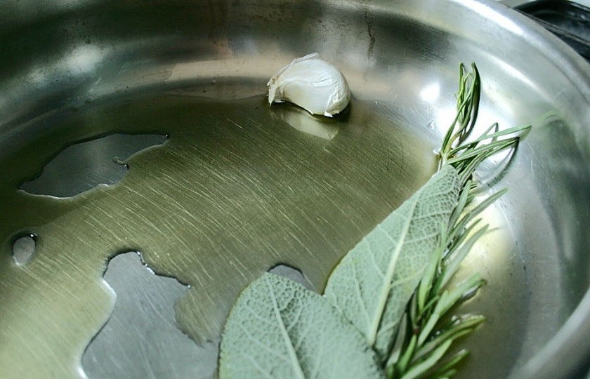 1. Этап. Запеченная говяжья вырезка в духовке: Расколите на сковороде оливковое масло, положите к нему зелень целиком и зубчик чеснока.