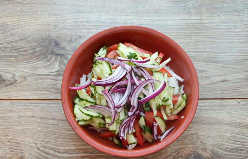 1. Этап. Салат с дайконом, огурцом и помидором: Репчатый лук почистите и порежьте тонкими перышками, выложите в миску с салатом.