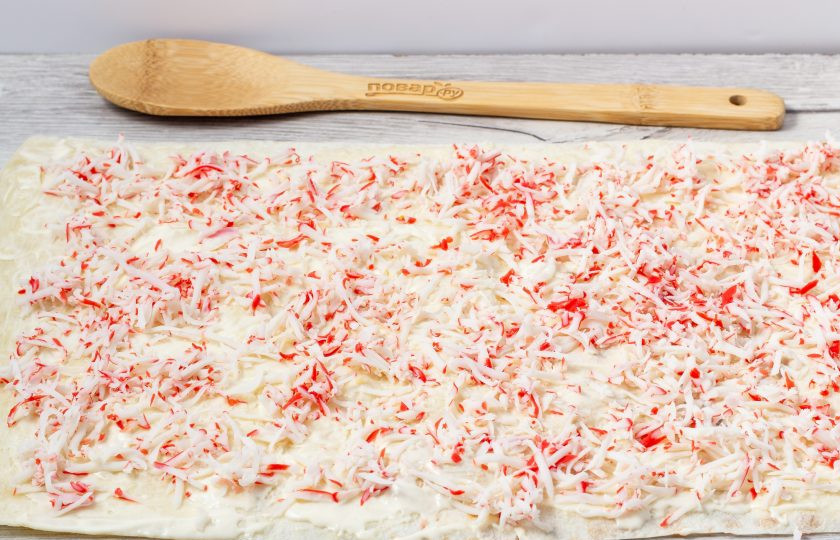 1. Этап. Завертон: Второй лаваш кладем на первый, смазываем майонезом и распределяем натертые крабовые палочки.