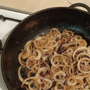 1. Этап. Печень говяжья с луком: Выложить лук на сковороду, где жарилась печень, и жарить, помешивая, до золотистого цвета.